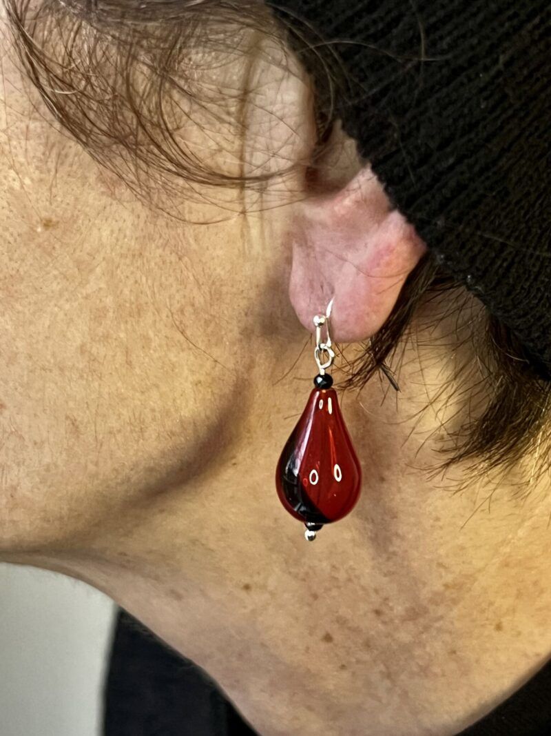 Øreringe med mundblæst glas perle i dråbe form i rødt glas med sort stribe.  Vælg i mellem forgyldt / forsølvet, eller Sterling sølv / forgyldt. Længden er ca. 4cm. Prisen er for et par.