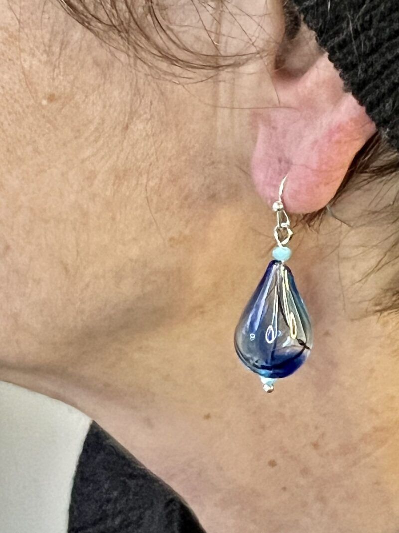 Øreringe med mundblæst glas perle i dråbe form i lys turkis/blå med sort stribe. Vælg i mellem forgyldt / forsølvet, eller Sterling sølv / forgyldt. Længden er ca. 4cm. Prisen er for et par.