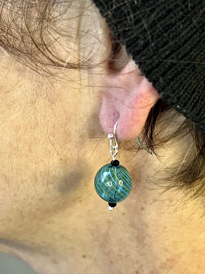 Øreringe med mundblæst glas rund perle i turkis med lys grønne og lys blå striber. Vælg i mellem forgyldt / forsølvet, eller Sterling sølv / forgyldt. Længden er ca. 3cm. Prisen er for et par.