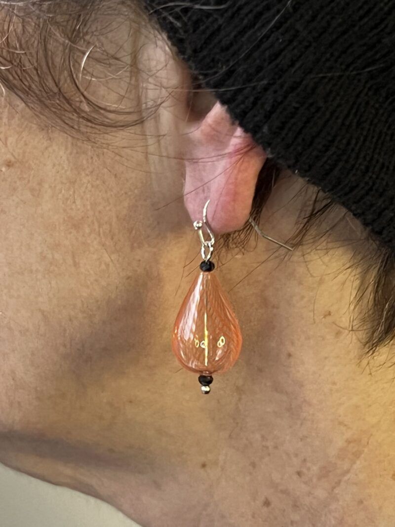 Øreringe med mundblæst glas perle i dråbe form i lys orange med orange striber. Vælg i mellem forgyldt / forsølvet, eller Sterling sølv / forgyldt. Længden er ca. 4cm. Prisen er for et par øreringe.